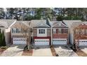 Charming townhomes with attached garages and brick and stone exteriors line a cozy neighborhood street at 545 Woodland Park Ter, Lawrenceville, GA 30043