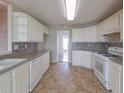 Well lit kitchen featuring tiled backsplash, white cabinets, stainless steel dishwasher and oven at 334 Royal Crescent Way, Stockbridge, GA 30281