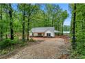 Exterior view of single story home on a tree covered lot with gravel driveway at 1765 Harmony Rd, Temple, GA 30179