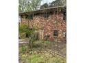 Two-story brick home with multiple windows needing repair, surrounded by overgrown vegetation and debris at 4216 Connor Dr, Ellenwood, GA 30294