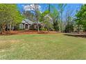 Expansive front lawn featuring a beautiful brick home surrounded by lush, mature trees at 423 Morgan Falls Chase, Canton, GA 30114
