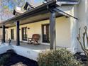 Inviting covered porch featuring brick columns, double glass doors, a rocking chair, and well-maintained landscaping at 1049 Panola Rd, Ellenwood, GA 30294