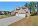 Side view of a two-story brick home with an attached two-car garage and a spacious driveway at 2021 Adam Acres Dr, Lawrenceville, GA 30043
