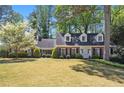 Charming two-story brick home with blue shutters and a lush front yard featuring a beautiful blossoming tree at 1000 N Harbor Ct, Atlanta, GA 30328