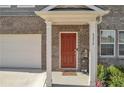 Inviting front entrance with a red door, decorative columns, and manicured landscaping at 5372 Fountain Head Ln, Auburn, GA 30011