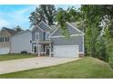 Charming two-story home showcasing gray siding, a two-car garage, and an expansive concrete driveway at 1097 Bodega Loop, Locust Grove, GA 30248