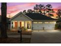 Charming single story home boasts a well-manicured lawn and attached two car garage during sunset at 126 Cottage Club Dr, Locust Grove, GA 30248