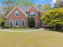 Inviting two-story brick home with a lush green lawn, complemented by mature landscaping and a welcoming entrance at 1870 Chattahoochee Run Dr, Suwanee, GA 30024
