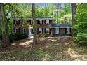 Charming two-story brick home with black shutters and a well-manicured front lawn in a wooded lot at 5145 Davantry Dr, Dunwoody, GA 30338