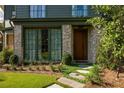 Charming home entrance with stone walkway, green grass, and brick accents, leading to a stylish dark wood door at 77 Delmont Ne Dr, Atlanta, GA 30305