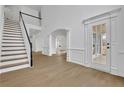 Bright entryway with stairs, white wainscoting, light floors, and archways to other rooms at 9429 Golfview Pt, Villa Rica, GA 30180