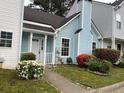 Exterior shot of light blue townhome featuring a black roof and a landscaped yard at 5961 Sherwood Trce, Stonecrest, GA 30038