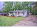 This ranch home features a well-manicured lawn, black shutters, and a concrete driveway at 2038 Thomasville Se Dr, Atlanta, GA 30315