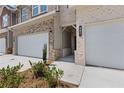 Close-up facade of a brick townhome with a two-car garage and well-kept landscaping at 847 Pensive Run, Dacula, GA 30019