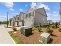 Exterior facade of townhomes with front lawns and utility boxes on a sunny day at 847 Pensive Run, Dacula, GA 30019
