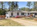Charming white brick home with manicured lawn, colorful flowerbeds, and a gravel driveway at 200 Heaton Park Dr, Decatur, GA 30030