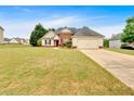 Expansive front lawn showcasing a charming one-story home with a two-car garage and traditional architectural details at 57 Craig Meadows Ln, Douglasville, GA 30134