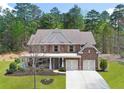 A beautiful house with a brick facade, a two-car garage, a large lawn, and a welcoming front porch at 1964 Crosswaters Dr, Dacula, GA 30019