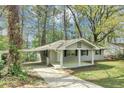 View of ranch-style home with a covered carport and fresh gray paint surrounded by mature trees and lawn at 3711 Daisy Dr, Decatur, GA 30032