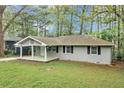Charming single-story home with a covered front porch and well-maintained lawn surrounded by mature trees at 3711 Daisy Dr, Decatur, GA 30032