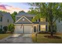 Charming two-story home featuring a two-car garage, manicured lawn, and mature tree during a sunset at 512 Watercress Dr, Woodstock, GA 30188