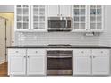 Close-up of kitchen with stainless steel oven, microwave, white cabinets, and black countertop at 625 Park Creek Trce, Alpharetta, GA 30005