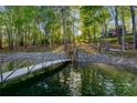 Private dock with a wooden walkway and stairs leading to the lake surrounded by lush trees at 6477 Old Shadburn Ferry Rd, Buford, GA 30518