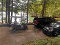 View of the driveway with a golf cart and parked cars next to the lake at 6477 Old Shadburn Ferry Rd, Buford, GA 30518