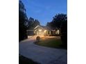Charming single-story home with manicured lawn, paved driveway and attached garages at dusk at 6477 Old Shadburn Ferry Rd, Buford, GA 30518