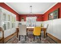 Bright dining room with red accent wall, wainscoting, wooden table, and stylish lighting fixture at 2964 Anderson Se Cir, Smyrna, GA 30080