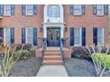 Welcoming brick front entrance with double doors, black shutters and decorative landscaping at 3045 Hartridge Dr, Johns Creek, GA 30022