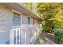 A view of the front porch, bright red front door, and painted brick of this charming single-story home at 8596 Timberlane Dr, Douglasville, GA 30134