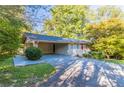 A single-story home with painted brick and a carport nestled among mature trees, offering shade and curb appeal at 8596 Timberlane Dr, Douglasville, GA 30134