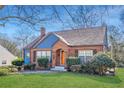 Charming brick home featuring an arched doorway, complemented by manicured landscaping on a lush lawn at 958 Winburn Dr, Atlanta, GA 30344