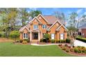 Beautiful red brick home with lush green lawn, a circular driveway, and mature landscaping at 7430 Polo Hl, Cumming, GA 30040