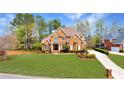 Attractive brick home with a spacious green lawn, a circular driveway, and mature trees at 7430 Polo Hl, Cumming, GA 30040