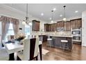 Stylish eat-in kitchen showcasing dark cabinetry, stainless steel appliances, an island, and modern pendant lighting at 15 Granville Ln, Covington, GA 30016