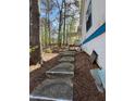 A concrete walkway leads to the rear of the home, surrounded by natural landscaping at 506 Carlton Dr, Palmetto, GA 30268
