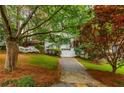 Classic white brick home with manicured lawn, and a tree-lined driveway offering scenic curb appeal at 648 Channing Nw Dr, Atlanta, GA 30318