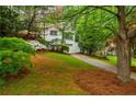 Traditional home with well-kept lawn and flower beds, features a white brick exterior, and attached garage at 648 Channing Nw Dr, Atlanta, GA 30318