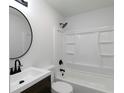 Updated bathroom features a shower-tub combo with a dark vanity, round mirror, and modern fixtures at 7965 Tower Dr, Douglasville, GA 30134