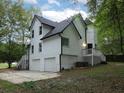 Side view of a two-story home with white siding, a black roof, an attached two-car garage, and a small deck at 7965 Tower Dr, Douglasville, GA 30134