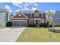 Traditional two-story brick home with a manicured lawn, a two-car garage, and charming front-yard garden at 3950 Almandine Way, Cumming, GA 30040