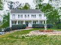 Two-story home featuring a large front yard with mature trees, a porch, and a second story balcony at 1606 Nuthatch Ct, Marietta, GA 30062