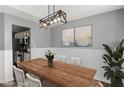 Elegant dining room with wood table, chandelier lighting, decorative wall paneling, and view of kitchen at 6332 Fairoaks Pl, Douglasville, GA 30135