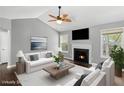 Bright living room featuring a fireplace, ceiling fan, modern furniture, and natural light from the windows at 6332 Fairoaks Pl, Douglasville, GA 30135
