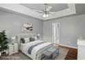 Calming main bedroom with tray ceiling, fan, ensuite bathroom, and bench seat at the foot of the bed at 6332 Fairoaks Pl, Douglasville, GA 30135