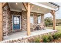 Charming brick front porch featuring wooden columns, rocking chairs, and a welcoming blue front door at 5109 Hillside Haven Dr, Powder Springs, GA 30127