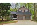 Charming two-story home with a two-car garage, surrounded by mature trees, providing a sense of privacy and tranquility at 5415 Keithwood Dr, Cumming, GA 30040