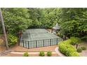 Private tennis court surrounded by lush greenery with viewing gazebo and fenced enclosure offers recreation and relaxation at 440 Old Homestead Trl, Johns Creek, GA 30097